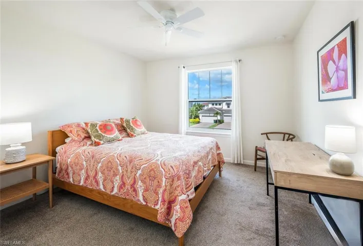 Carpeted bedroom with ceiling fan and baseboards