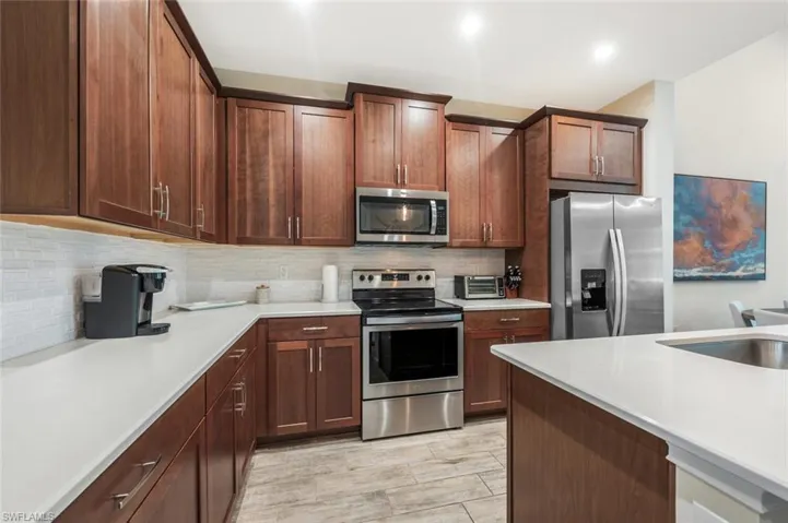 Kitchen featuring stainless steel appliances, backsplash, light countertops, and recessed lighting