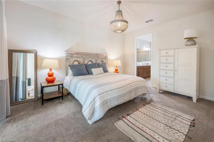 Bedroom with carpet, a chandelier, and connected bathroom