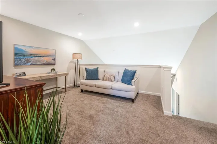 Living room with light colored carpet, vaulted ceiling, and recessed lighting