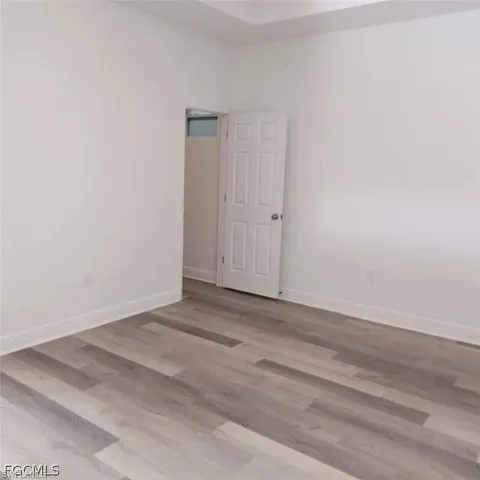 Room featuring light wood-finish flooring, white baseboards, and bright white walls