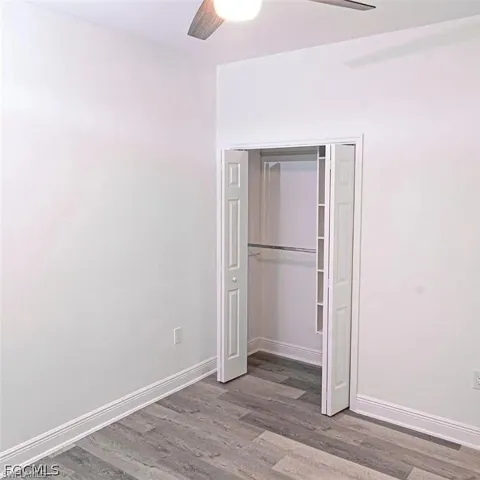 Room featuring wood-finish flooring, white baseboards, and a ceiling fan with integrated lighting