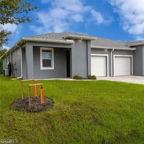 Contemporary stucco exterior with a gray finish, featuring a two-car garage with white doors, a covered entry, and a contrasting white window frame