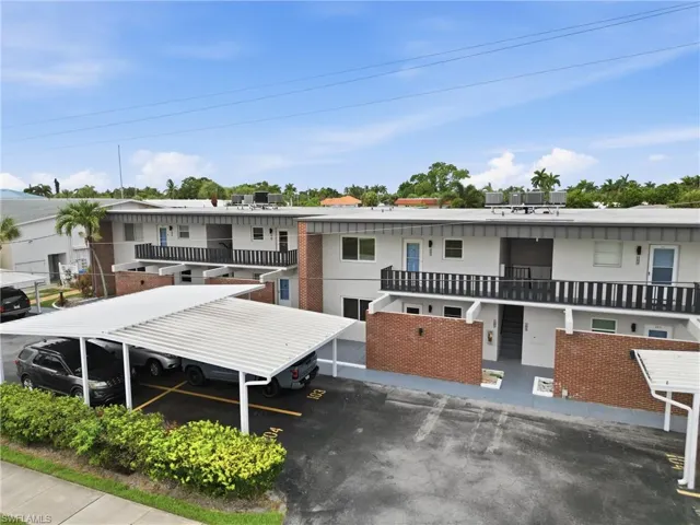 Multi-unit property featuring two stories of residences, covered parking structures, and exterior brick walls