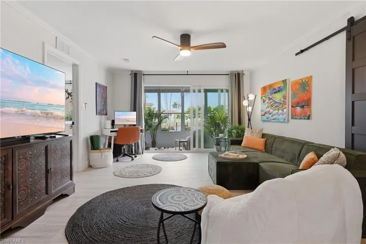 Open-concept living area with light wood-finish flooring, a contemporary ceiling fan, built-in desk area, and sliding glass doors to outdoor space