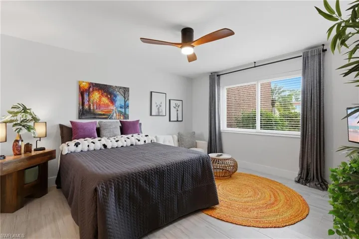 Light-toned wood-finish flooring provides a neutral backdrop for a large window featuring horizontal blinds