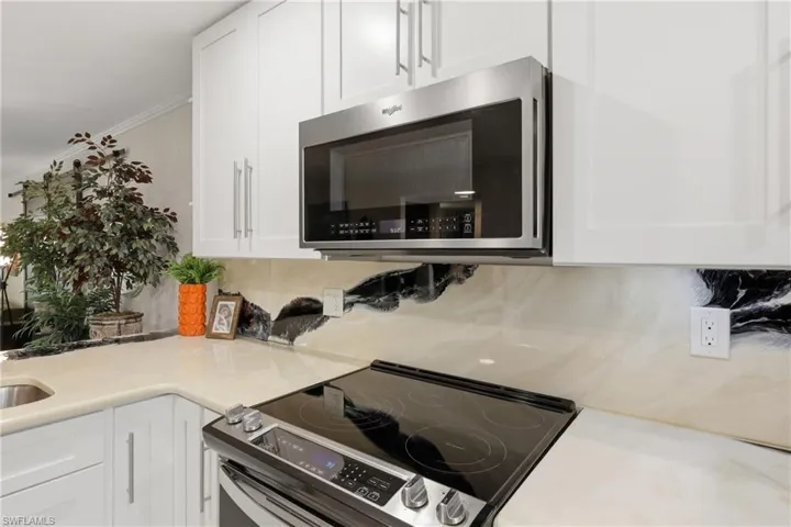 Modern kitchen featuring white shaker cabinetry, light-toned countertops, and a black and white patterned backsplash