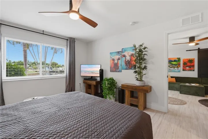 Bright interior featuring a ceiling fan with integrated lighting, wood-finish flooring, and a large window with blinds