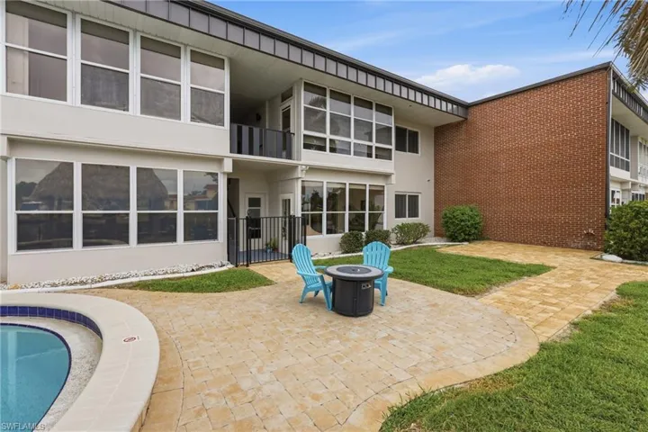 Expansive paver patio with a curved border, featuring a built-in pool with a tiled edge