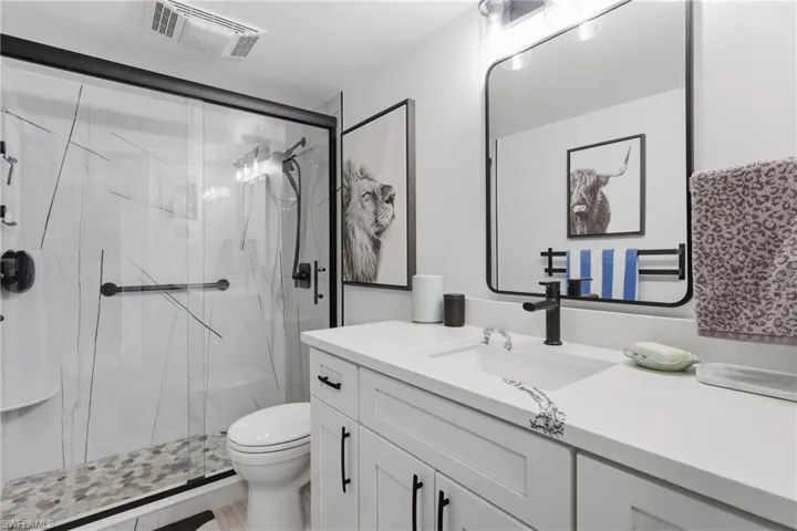 Modern full bathroom featuring a white vanity with integrated sink, black framed mirror, and matte black fixtures