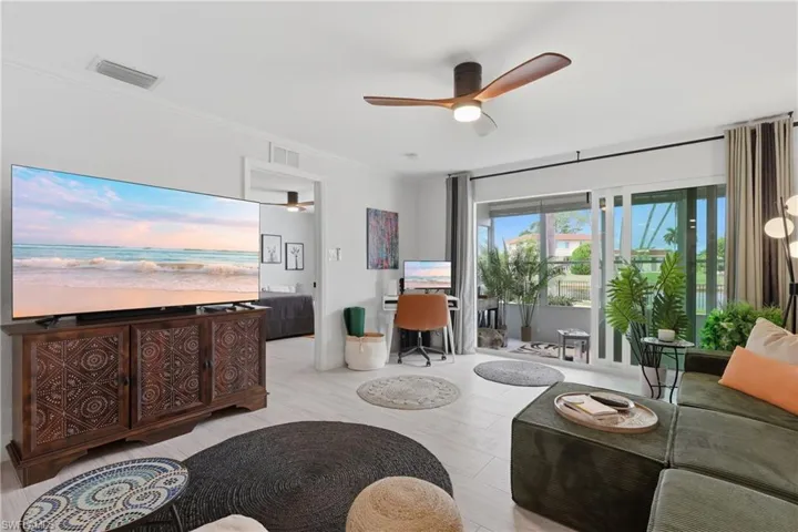 Bright living area featuring light wood-finish flooring and a contemporary ceiling fan