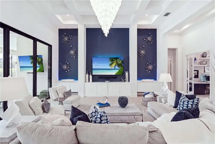 Tray ceiling with recessed lighting, black-framed glass sliding doors, built-in display cabinetry, wood-finish flooring, and a large central chandelier