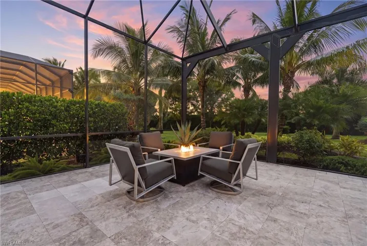 Screened outdoor patio featuring a fire pit, tile flooring, and lush landscaping