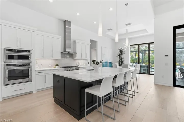 Gourmet kitchen featuring a large central island, white cabinetry, stainless steel appliances, and wood-finish flooring