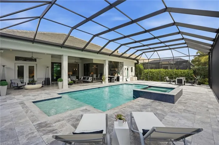 Screened lanai featuring a swimming pool, integrated spa, and expansive patio with tile flooring
