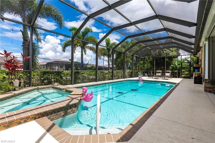 View of swimming pool with a patio, glass enclosure, and an in ground hot tub