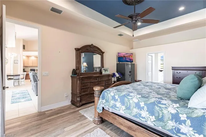 Tiled bedroom with ceiling fan and a tray ceiling