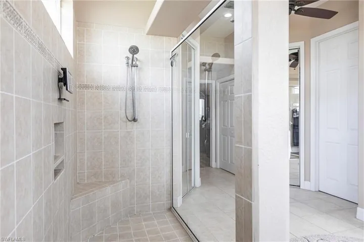 Bathroom featuring tile floors, ceiling fan, and an enclosed shower