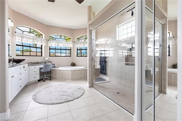 Bathroom with tile floors, ceiling fan, vanity, and independent shower and bath