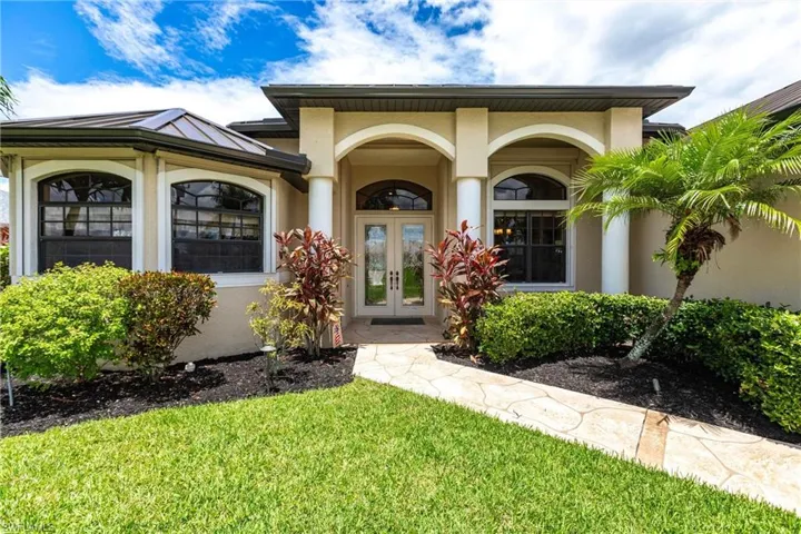 View of exterior entry featuring french doors and a yard