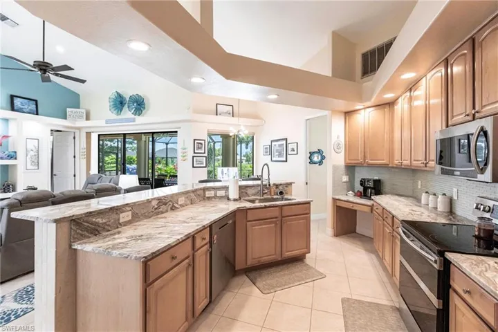 Kitchen with ceiling fan, tasteful backsplash, high vaulted ceiling, appliances with stainless steel finishes, and sink
