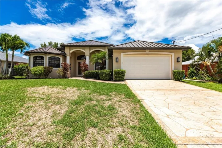 View of front of property featuring a garage and a front lawn
