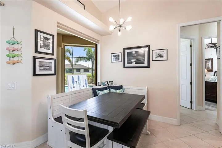 Tiled dining space featuring a notable chandelier and vaulted ceiling