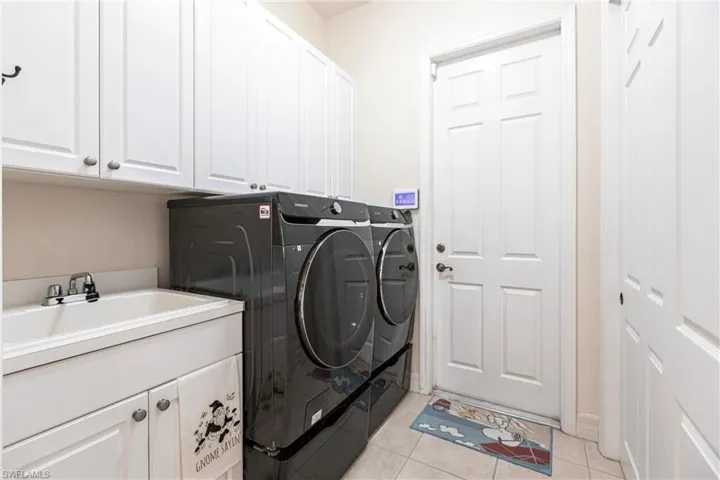 Washroom featuring cabinets, sink, washing machine and dryer, and light tile flooring