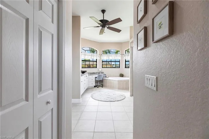 Bathroom featuring tile floors, vanity, tiled bath, and ceiling fan