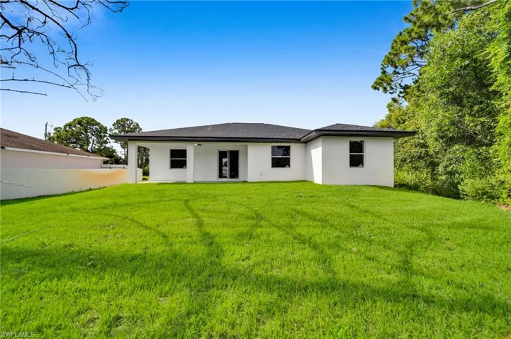 Rear view of house with a lawn, a patio, and stucco siding