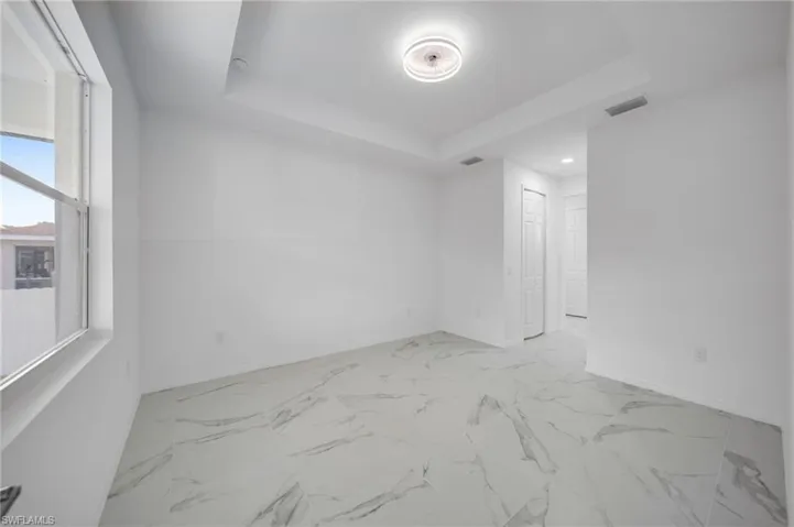 Unfurnished room with baseboards and a tray ceiling