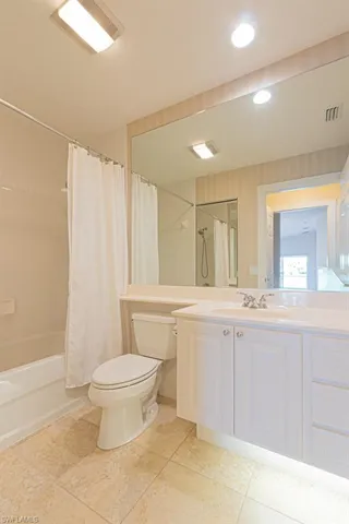 Bathroom with vanity, shower / bathtub combination with curtain, light tile patterned floors, and recessed lighting