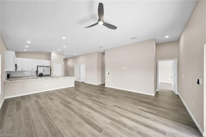Unfurnished living room with light hardwood / wood-style floors, ceiling fan, and lofted ceiling