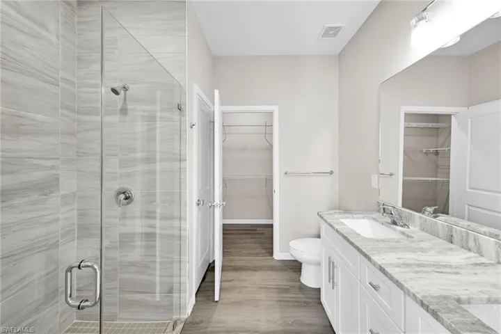 Bathroom with hardwood / wood-style floors, vanity, toilet, and a shower with shower door