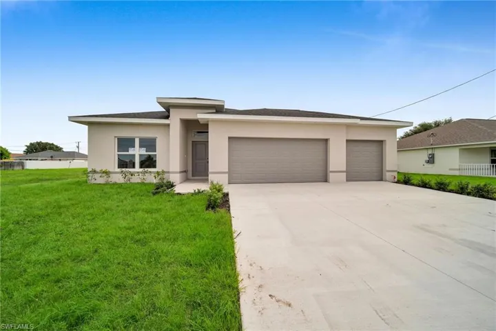 View of front facade featuring a garage and a front lawn