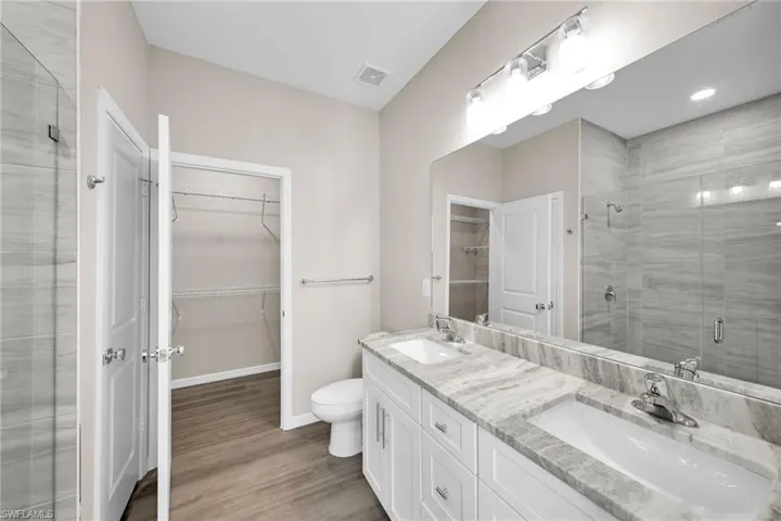 Bathroom with hardwood / wood-style flooring, vanity, toilet, and an enclosed shower