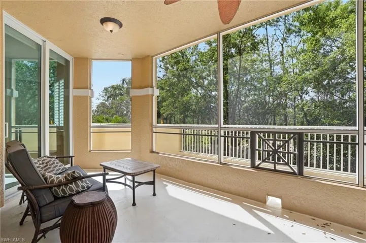 The property features a screened-in lanai with a textured ceiling, a ceiling fan, and views of lush greenery