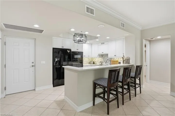 The kitchen features white cabinetry, a tiled backsplash, and recessed lighting