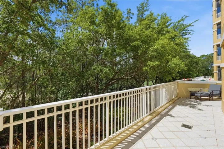 The property features an outdoor patio with a white railing and tiled flooring, providing tree-lined views