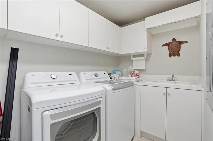 The laundry area features white cabinetry, a sink with a faucet, and white appliances