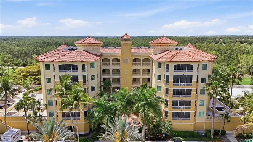 This property features a multi-story building with a light-colored facade and a red tile roof