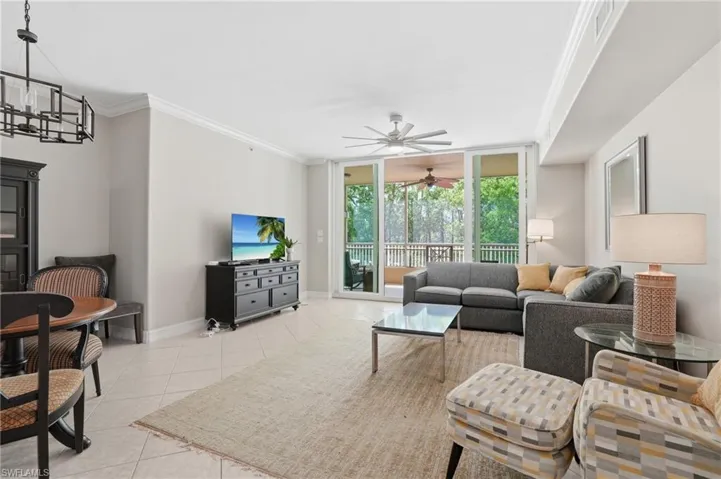 The living area features tile flooring, crown molding, and direct access to a private balcony through sliding glass doors