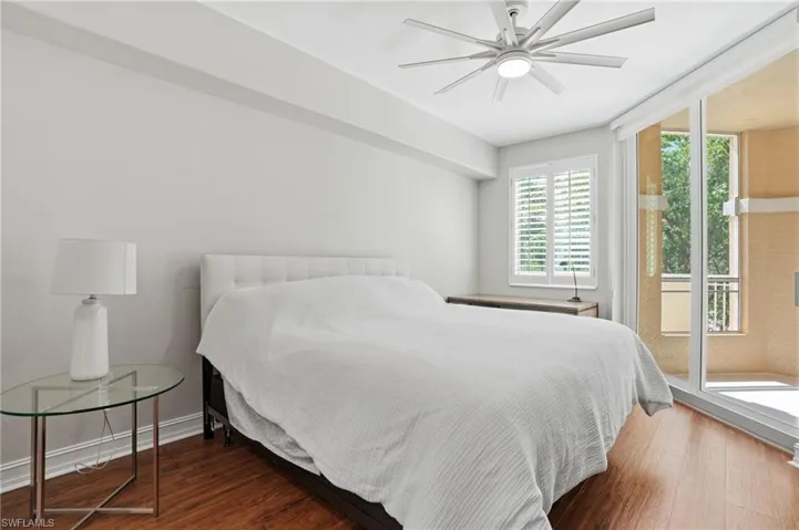 This room features hardwood flooring, a ceiling fan with light, and white walls