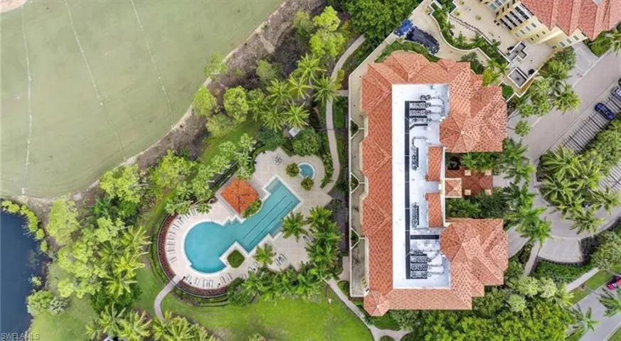 Aerial view of the property and its amenities, featuring a swimming pool, lounge area, and surrounding green spaces