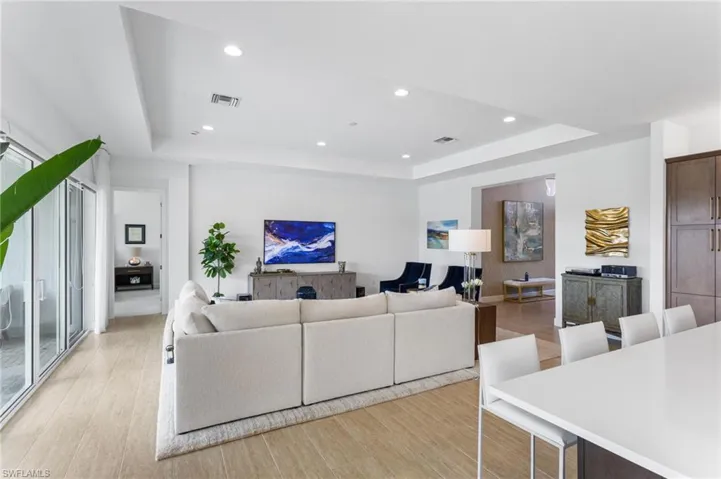 Living area featuring a raised ceiling, recessed lighting, and light wood-type flooring