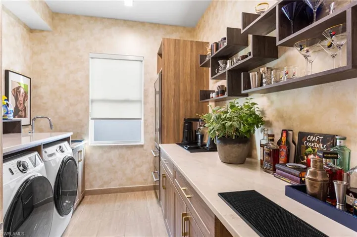 Laundry area featuring washing machine and clothes dryer, light tile patterned flooring, and wallpapered walls