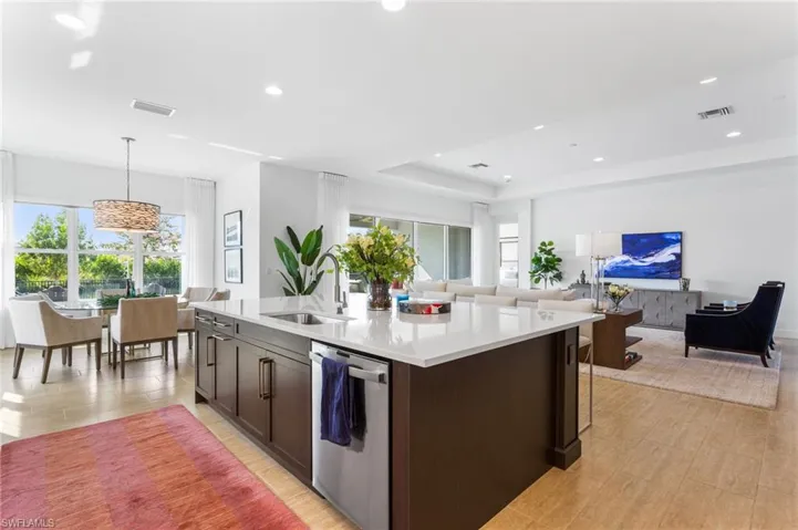 Kitchen featuring pendant lighting, dishwasher, open floor plan, dark brown cabinets, and a tray ceiling