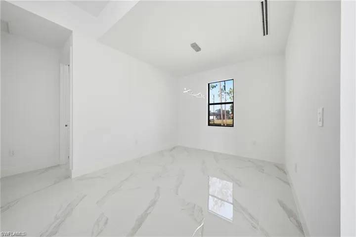 Spacious interior featuring white walls, large format tile flooring, and a window with a black frame