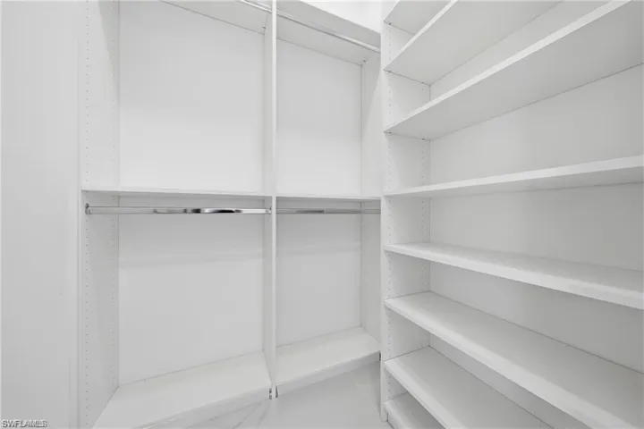 Walk-in closet with extensive built-in shelving, multiple hanging rods, and adjustable shelf heights