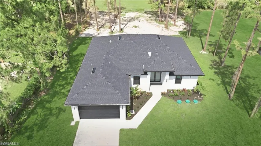 Modern residence with a dark shingle roof, white exterior, and an attached garage with a dark door